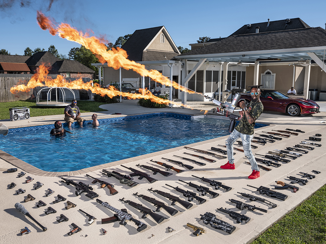 12_Gabriele Galimberti_for National Geographic.jpg - Schiever, Louisiana - Torrell Jasper, a.k.a. Black Rambo [35]  - Every day, nearly nine hundred thousand people wait for Torrell Jasper to make his appearance on Instagram and show off one of his guns. To find him, just type in â€œBlack Ramboâ€�, a nickname heâ€™s extremely proud of, and make sure you donâ€™t end up on his sonâ€™s account by mistake (at 13, heâ€™s already trying to make a name for himself on social media). Torrell, now 35, learned to shoot from his father as a child. A former Marine, he spent a few years in war zones, â€œwhere pulling the trigger and hitting the target was a question of life or death.â€� Now, back in civilian life and working as an A/C systems installer, Torrell, a.k.a. Black Rambo, mostly just has fun with his guns. People have fun watching him, too. â€œThere are no weapons I would ban ordinary citizens from owning, but if I had to name one, well, a bazooka isnâ€™t really something you need,â€� he admits.